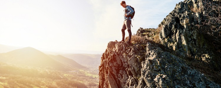 young male traveller standing on high cliff