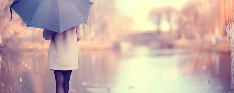 Woman standing under an umbrella next to a lake