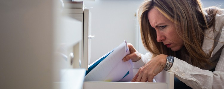 A woman searching through documents in an open draw