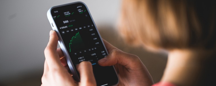 young woman holding a smartphone looking at investment performance