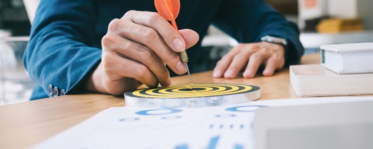 businessman holding a dart aiming at the centre of the target