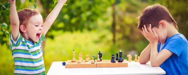 two boys playing chess, one has just won the game and is celebrating