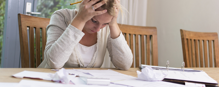 woman looking stressed with paperwork all over the table