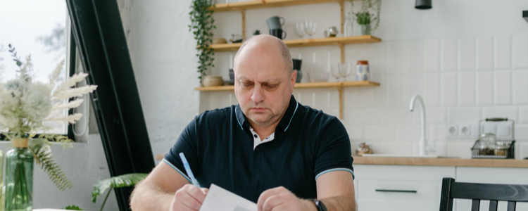 man sitting at kitchen table with paperwork