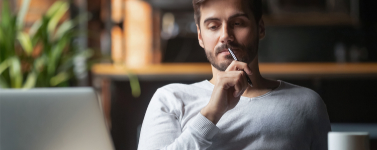 man sitting in front of a laptop thinking