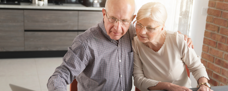 Senior couple reviewing investments on laptop