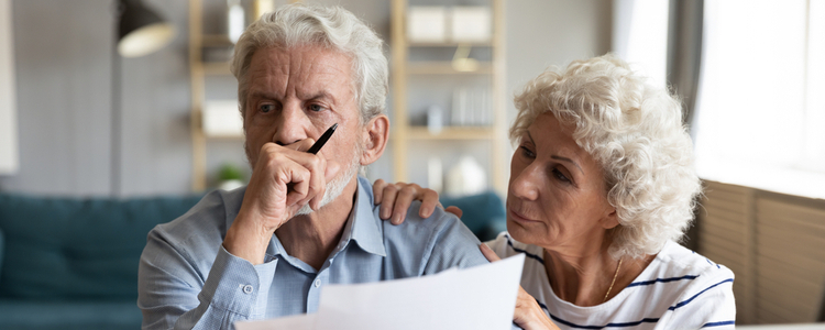 Worried senior couple reviewing financial paperwork