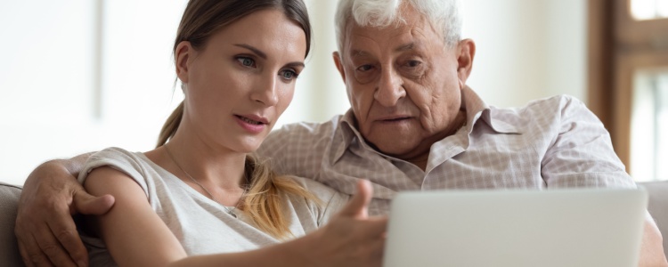 young woman helping her grandfather to use a laptop
