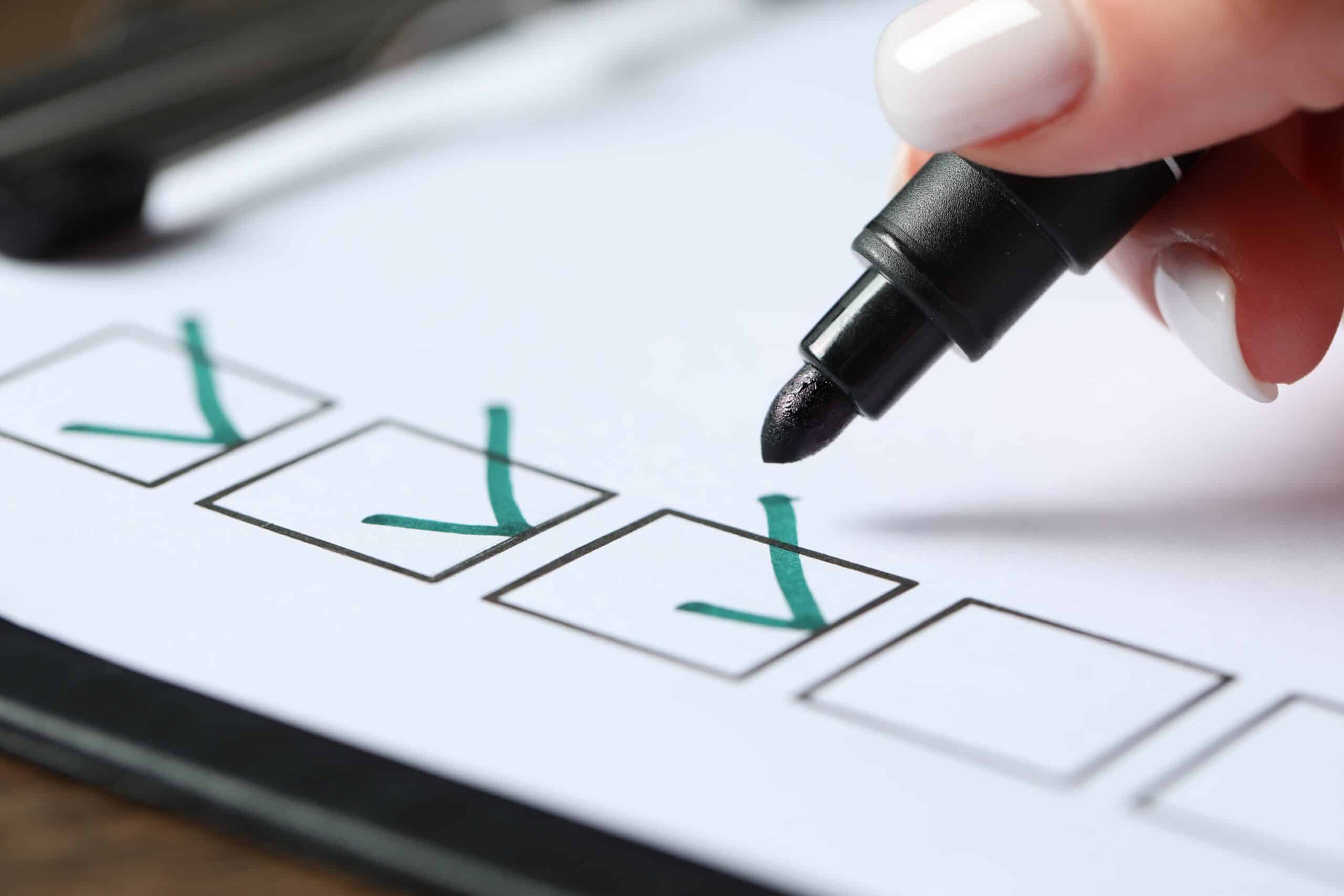 A woman’s hand marking a checklist with a pen