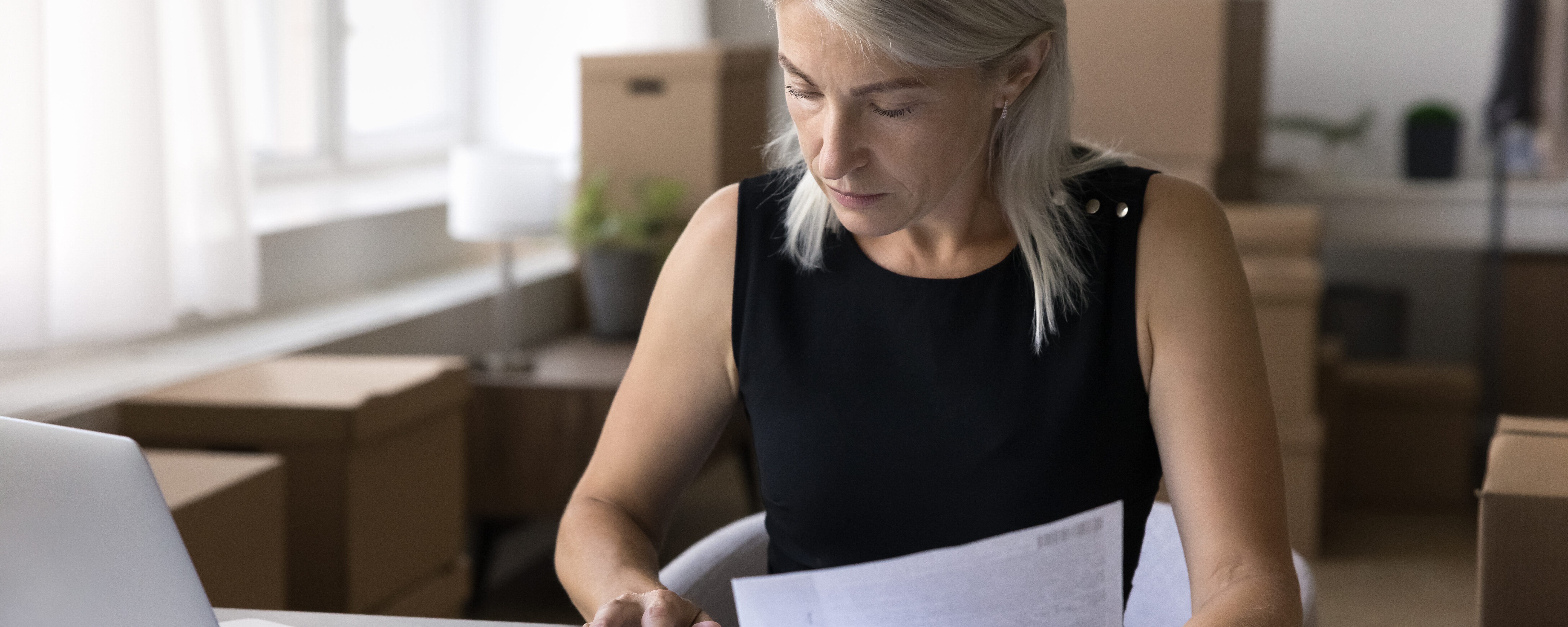 Middle-aged self-employed woman using a calculator and looking at paperwork